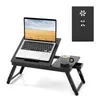 A black wooden laptop table with a laptop, a mug, and a small drawer.