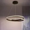 A modern LED pendant light fixture with two intertwined rings, suspended from a ceiling. Produktbild-Vorschau