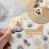 A hand holding a sticker with a Ramadan-themed design, with a larger Ramadan calendar in the background. Produktbild-Vorschau