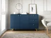 A navy blue sideboard with gold accents is shown in a living room setting, next to a chair and a rug. Podgląd zdjęcia produktu