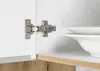 A close-up view of a cabinet hinge and a stack of white plates inside a cabinet. Produktbild-Vorschau