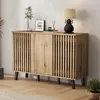 A wooden sideboard with a slatted front is placed against a textured wall, decorated with a lamp, a framed picture, and some decorative items. Anteprima dell’immagine prodotto