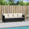 A black poly rattan sofa with white cushions is placed on a tiled patio next to a swimming pool, with a wooden fence in the background. Produktbild-Vorschau