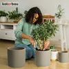 A woman is repotting a plant in a living room setting. Náhled obrázku produktu