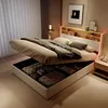 A modern bedroom with a bed that has its storage compartment open, revealing stored items. The bed has LED lighting. Produktbild-Vorschau