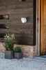 A dark wooden wall with a white light fixture and two planters with green plants. Produktbild-Vorschau