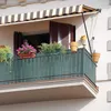 A balcony with plants and a striped awning. Podgląd zdjęcia produktu