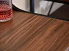 A close-up view of a wooden tabletop with a glass of red liquid on the left side. Náhled obrázku produktu