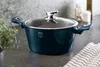 A dark teal pot with a glass lid sits on a countertop next to a plant and a checkered cloth. Anteprima dell’immagine prodotto