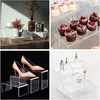 A collage of four images showcasing clear acrylic display stands in various settings, including home decor, dessert presentation, shoe display, and perfume arrangement. Produktbild-Vorschau