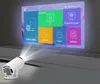 A white projector is projecting a colorful menu screen onto a wall. The menu has icons and text for various functions like 'Online video', 'Projection', 'My Apps', 'Local', 'Projection screen', and 'Settings'. Náhled obrázku produktu