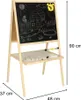 A wooden easel with a chalkboard and a whiteboard, showing children's drawings and writing tools. Podgląd zdjęcia produktu