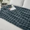 A dark gray plush blanket is spread across a bed with white pillows in the background. Produktbild-Vorschau