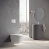 A modern bathroom with a wall-hung toilet and a cylindrical sink, overlooking a city skyline. Anteprima dell’immagine prodotto