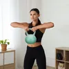 A woman is performing a workout with a kettlebell in a home gym setting. Náhled obrázku produktu