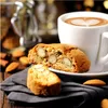 A close-up of almond biscotti next to a cup of coffee with latte art. Produktbild-Vorschau