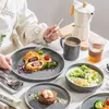 A person is having a meal with a set of dishes, coffee maker, and drinks on a table. Náhled obrázku produktu