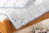 A white comforter with blue trim is laid out on a wooden bed frame. A label with the brand name 'PROCAVE' is visible on the comforter. Produktbild-Vorschau