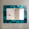 A decorative wall mirror with a green leaf motif frame, displayed on a concrete wall. Produktbild-Vorschau