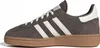 A side view of a brown Adidas Handball Spezial sneaker with white stripes and laces, set against a white background. Voir les images du produit