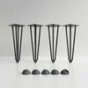Four black hairpin legs and four black floor protectors are displayed on a white surface against a light gray background. Anteprima dell’immagine prodotto
