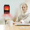 A woman sits at a desk with a laptop and mug, while a small electric heater with a flame effect is mounted on the wall. Anteprima dell’immagine prodotto