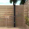 An outdoor shower with a wooden slatted fence and stone wall background, with palm trees and cacti visible. Produktbild-Vorschau