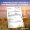 A document with test results is placed in front of a sunset beach background. Produktbild-Vorschau