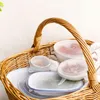 A wicker basket filled with reusable silicone food covers and containers. Produktbild-Vorschau
