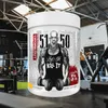 A supplement container is placed in a gym setting. Produktbild-Vorschau