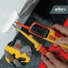 Hands holding electrical testers near a wall socket. Náhľad obrázku produktu