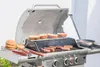 A barbecue grill with food cooking on it, including burgers and buns, and a pan with vegetables on the side. Náhled obrázku produktu
