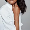 A woman wearing a white shirt and a Pandora bracelet with a charm. Produktbild-Vorschau
