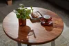 A round wooden coffee table with a plant, a pastry, and a cup of coffee on it. Náhľad obrázku produktu