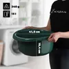 A person holding a dark green plastic basin in a laundry room setting. Podgląd zdjęcia produktu