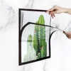Hands are shown attaching a magnetic frame to a diamond painting of cacti. Podgląd zdjęcia produktu