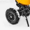 A close-up view of a yellow and black spreader with snow on its wheel and frame, resting on a snowy surface. Produktbild-Vorschau