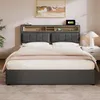 A bed with a headboard featuring storage shelves and a charging station, set in a bedroom. Produktbild-Vorschau