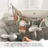 A baby's hand reaching for a mobile hanging over a crib. Produktbild-Vorschau
