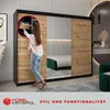 A woman is organizing clothes in a modern sliding door wardrobe with a mirror in a bedroom setting. Produktbild-Vorschau