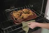 A person is taking a tray of fried chicken out of an oven. Podgląd zdjęcia produktu