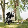 A woman pushing a stroller in a park. Produktbild-Vorschau