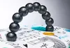 A close-up of a black beaded handle arching over a white fabric surface with a Parisian-themed print. Náhľad obrázku produktu