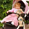 A baby sitting in a stroller with stuffed animals and a pink blanket. Produktbild-Vorschau