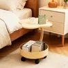 A small yellow side table with a round storage bin at the bottom, placed next to a bed and a nightstand. Produktbild-Vorschau