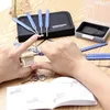 Hands are shown using a lock picking set on a wooden table, with a manual and other tools scattered around. Produktbild-Vorschau