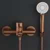 A copper-colored shower faucet and handheld shower head are mounted on a dark gray wall. Náhľad obrázku produktu