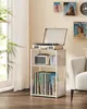 A record player stand with records and a record player on top, placed near a window with sheer curtains. Produktbild-Vorschau