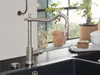 A kitchen faucet is shown on a black countertop with a sink and a window with plants in the background. Produktbild-Vorschau