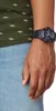 A close-up shot of a person's wrist wearing a black watch. Produktbild-Vorschau